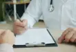 Ein Arzt bespricht mit einer Patientin oder einem Patienten medizinische Unterlagen an einem Schreibtisch.