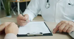 Ein Arzt bespricht mit einer Patientin oder einem Patienten medizinische Unterlagen an einem Schreibtisch.