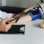 Eine medizinische Fachkraft misst mit einer Oberarmmanschette den Blutdruck einer Patientin.