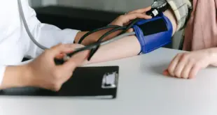Eine medizinische Fachkraft misst mit einer Oberarmmanschette den Blutdruck einer Patientin.