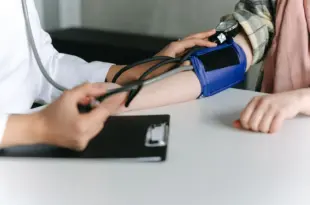 Eine medizinische Fachkraft misst mit einer Oberarmmanschette den Blutdruck einer Patientin.