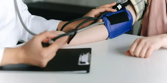 Eine medizinische Fachkraft misst mit einer Oberarmmanschette den Blutdruck einer Patientin.