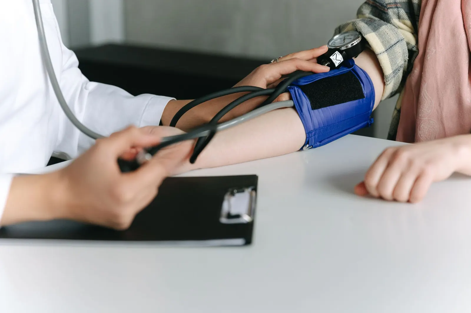 Eine medizinische Fachkraft misst mit einer Oberarmmanschette den Blutdruck einer Patientin.