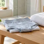 Gefaltete Unterwäsche und ein Handtuch auf einer Holzbank