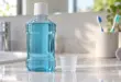 Eine unbeschriftete Flasche mit blauer Flüssigkeit und ein Messbecher auf einer Badezimmerablage