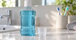 Eine unbeschriftete Flasche mit blauer Flüssigkeit und ein Messbecher auf einer Badezimmerablage