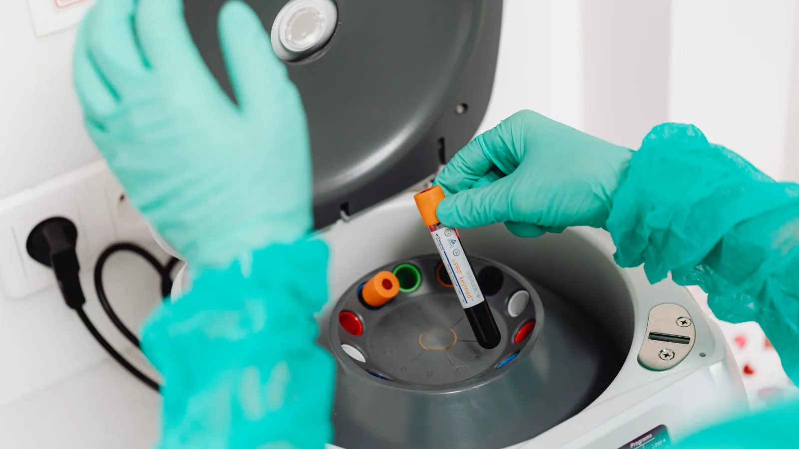Laborfachkraft stellt eine Blutprobe in eine Zentrifuge